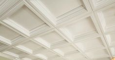 a living room filled with lots of white furniture and walls covered in decorative ceiling tiles