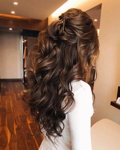 the back of a woman's head with long wavy hair in a half updo