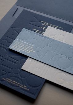 two blue and white business cards sitting on top of each other next to each other