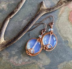 Indulge in the exquisite beauty of our Wire Wrapped Opalite Earrings! These captivating dangle earrings showcase 12mm blue Opalite beads delicately wrapped in warm antiqued copper wire. Whether for everyday wear or a special occasion, they hang elegantly at 1 inch from copper french earwires. Experience the versatility and allure of these earrings for yourself!  Thank you for taking the time to visit my shop. If you have any questions, please don't hesitate to contact me. Blue Wire-wrapped Round Earrings, Blue Wire Wrapped Round Earrings, Opalite Earrings, Copper Earrings, Wire Wrap, Antique Copper, Copper Wire, Making Ideas, Wire Wrapped