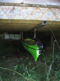 a green kayak is tied to the side of a building under an overpass