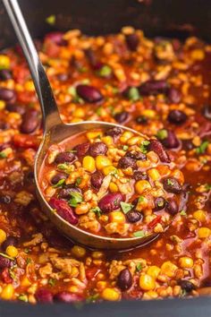 a spoon full of beans and corn in a large pot with the lid open to show it's contents