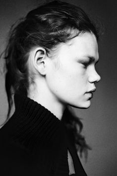 a black and white photo of a woman with her hair in a pony tail bun