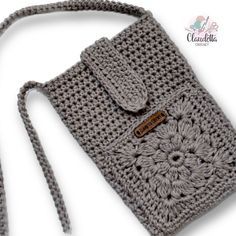 a gray crocheted purse with a brown button on the side and a white background