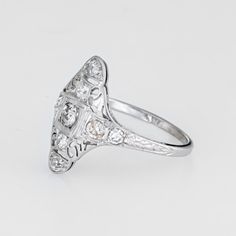 This is part of Chairish’s Fine Jewelry assortment.  Finely detailed vintage Art Deco era ring (circa 1920s to 1930s) crafted in 18k white gold.   Nine old mine cut diamonds total an estimated 0.60 carats (estimated at I-J colour and SI2-I1 clarity).   The ring features a lacy filigree design with an elongated mount, a hallmark of the Art Deco era. The mount has a slightly curved saddle for a comfortable fit on the finger. The ring has a low profile rising 4mm from the finger (0.15 inches).    T Antique Platinum Diamond Ring With Diamond Accents, Victorian White Gold Diamond Ring, Victorian Diamond Ring In White Gold, Antique Platinum Rings In Diamond White, Antique Platinum Ring In Diamond White, Victorian Style Diamond White Diamond Ring, Victorian Style White Diamond Platinum Ring, Victorian Diamond White Diamond Ring, Victorian Platinum Diamond Ring With Single Cut Diamonds