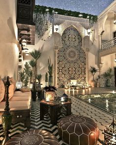 the interior of an ornately decorated room with potted plants and candles on tables