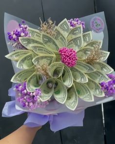 a bouquet made out of dollar bills and purple flowers