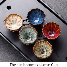 four different colored bowls sitting on top of a black tray with the words, the kiln becomes a lotus cup