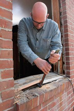 a man is working on a window sill with a naildriver in his hand