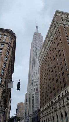 the empire building towering over other tall buildings in new york city, ny on a cloudy day