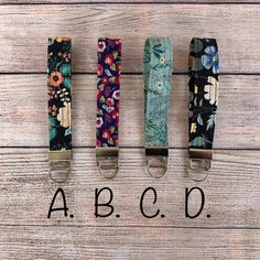 four key fobs with flowers on them and the word abcq written in black