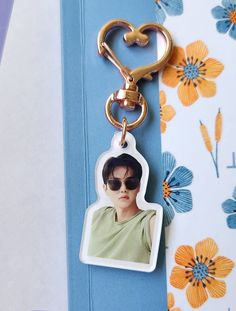 a keychain with a photo of a person wearing sunglasses on it and a flowered background