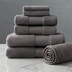 a stack of folded towels sitting on top of a white marble counter next to a rolled up towel