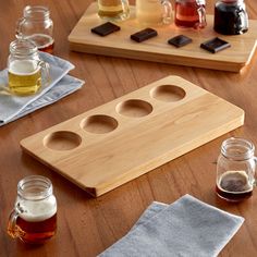 a wooden cutting board sitting on top of a table next to jars filled with liquid