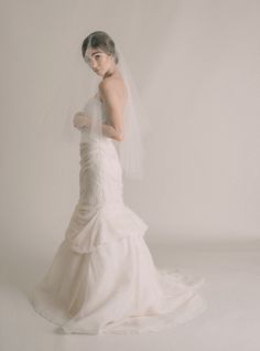 a woman in a wedding dress and veil posing for the camera with her hands on her hips