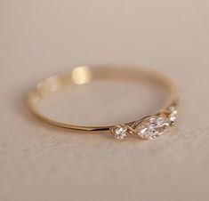 a yellow gold ring with two pear shaped diamonds on the side, sitting on a white surface