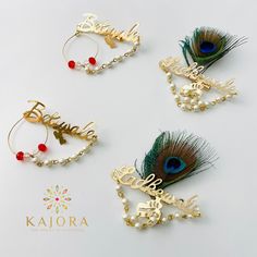 four pairs of hair clips with peacock feathers and name charms on them, all adorned with pearls