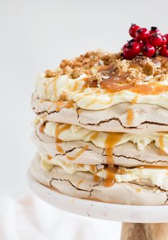 a layered cake with cranberry toppings and white icing on a plate