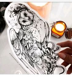 a hand holding an owl sticker next to a candle