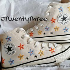 white converse sneakers with multicolored flowers on them