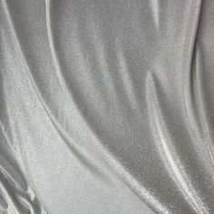 Make a statement with this shimmery silver Lurex Glitter Fabric! This luxurious fabric is perfect for creating stunning gowns, apparel, costumes, party wear, and more. The grey lurex has a two-tone palette/ iridescent look, and is full of glitter, giving it a beautiful shine and sparkle. It stretches on the width side only, and drapes gorgeously, sure to stand out at any event with its beautiful sparkles. The back side of the fabric is white, and made of lurex polyester. Our photographs are as a Silver Fabric, Luxurious Fabric, Stunning Gowns, Glitter Fabric, Silver Glitter, Luxury Fabrics, Winter Wonderland, Party Wear, Light Grey