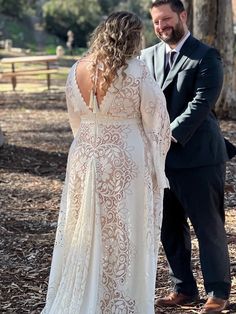 a man and woman standing next to each other in front of trees with their backs turned