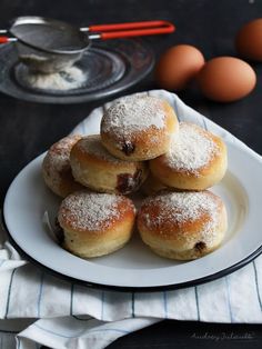 powdered sugar covered doughnuts on a plate next to eggs and utensils