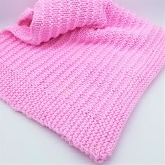 a pink knitted blanket laying on top of a white table