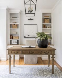 a home office with built in bookcases and a wooden desk topped with a potted plant