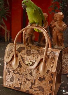 Expertly crafted by skilled artisans, the ALLE "ROMMY" is a stunning masterpiece! This hand-tooled leather weekender and Duffel bag showcases traditional techniques and high-quality cowhide. Versatile and stylish, it's the perfect companion for weekend getaways or as a carry-on for longer travels. The unique tooling adds a touch of sophistication, while the spacious design allows for easy organization and access to your essentials. Made from Full-grain leather, each bag varies in shading due to the thickness, which is determined by the animal's age and the natural creases of the leather itself. Hence, each bag's color and characteristics are truly one-of-a-kind. Details: Size 16"W x 12"H x 9" D (width is measured across the bottom of the purse) The interior features a zip-pocket Metal clos Luxury Hand Tooled Bags For Gifts, Artisan Engraved Rectangular Bag, Artisan Rectangular Engraved Bag, Artisan Rectangular Engraved Bags, Mexican Purse, Tooled Leather Purse, Leather Weekender, Hand Tooled Leather, Duffel Bags