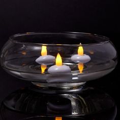 four candles are lit in a glass bowl