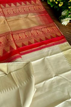 This stunning kanjivaram saree is handwoven in tussar white woven in ettu kol technique. The borders have an ettu kol temple reku woven in gold zari. The grand pallu in vermilion red color features an ettu kol band in gold zari bordering with peacocks and traditional motifs. Approximate Length 6.5 mtrs (inclusive of blouse length) Approximate Height - 48 - 52" Approximate weight - 1.7 lbs Saree comes with fall, picot and tassels done when applicable. Blouse piece is cut. Kindly Note : The colors White Traditional Wear With Traditional Patterns For Rituals, White Handloom Traditional Wear For Rituals, White Silk Dupatta With Border, Festive Saree With Border For Rituals, White Traditional Wear With Cutdana For Rituals, White Cutdana Traditional Wear For Rituals, White Paithani Silk Handloom Dupatta, Raw Silk Saree With Weaving Work For Rituals, Traditional Art Silk Saree In Off White