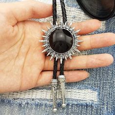 This awesome bolo tie has a southwestern design and black centerpiece.The cord is genuine leather.Our bolos pair nicely with many of our belt buckles! They make wonderful gifts.The western bolo tie rope length is 39'' ; charm pendant size is 1 3/4'' Southwestern Style Adjustable Bolo Ties, Concho Jewelry For Rodeo, Adjustable Concho Jewelry For Rodeo, Vintage Style Concho Lariat Necklace, Vintage Concho Lariat Necklace, Concho Lariat Bolo Tie For Western-themed Events, Concho Bolo Ties For Western-themed Events, Adjustable Concho Bolo Ties For Ranch, Southwestern Concho Bolo Tie For Ranch