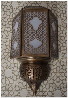 a wall light hanging from the side of a wall with an intricate design on it