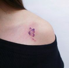 a woman's shoulder with a purple butterfly tattoo on her left shoulder and right arm