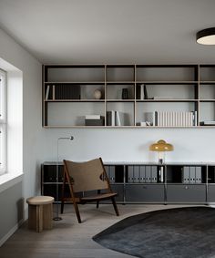 a living room filled with furniture and bookshelves next to a window on top of a hard wood floor