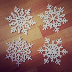 four white snowflakes sitting on top of a wooden floor