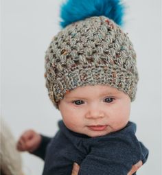 a baby wearing a knitted hat with blue pom - poms