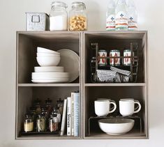 the shelves are organized with dishes and cups