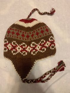 a brown and red knitted hat on top of a white sheet