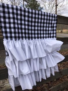 a black and white checkered blanket hanging on a fence with ruffles at the bottom