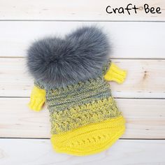 a crocheted mitten with a fur ball on it and the words craft bee written above it