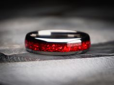 a close up of a wedding ring with red glitter on it's side and an arrow in the middle