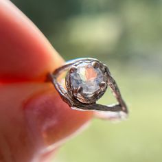 a close up of a person's hand holding a ring with a diamond in it