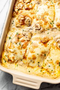 a casserole dish with mushrooms and cheese in it on a marble countertop