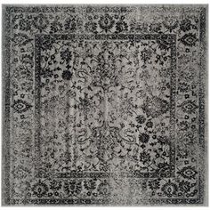 an area rug with black and white floral designs on the center, in front of a gray background