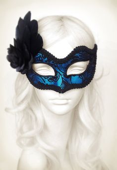 Venetian style masquerade mask covered black lace on metallic silver surface. Framed with black braided trim, small black rhinestones on the corners of the eyes. Decorated with black satin rose and black feathers. Your order will be delivered with online tracking by UPS or FedEx. Back surface is also covered with fabric for comfortable use. Ribbons are added both sides to tie. Base mask is made of paper mache. Standard size fits most (for women). This classical Venetian mask is perfect for any c Blue Masquerade Mask For Halloween Costume Party, Blue Masks And Prosthetics For Halloween Costume Party, Blue Masquerade Mask For Halloween Party, Fitted Masquerade Mask For Mardi Gras, Blue Masquerade Mask For Halloween, Blue Halloween Masquerade Mask, Blue Venetian Masquerade Mask For Party, Blue Party Eye Mask, Fitted Eye Mask For Carnival Masquerade