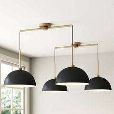 three black and gold lights hanging from the ceiling above a dining room table with chairs