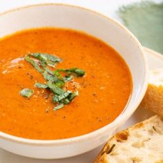 a bowl of tomato soup with bread on the side