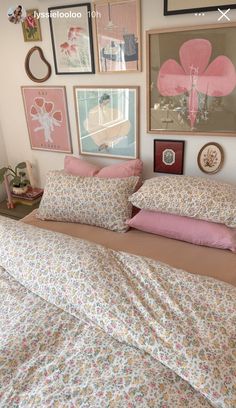 a bed covered in pink and white sheets next to pictures on the wall above it